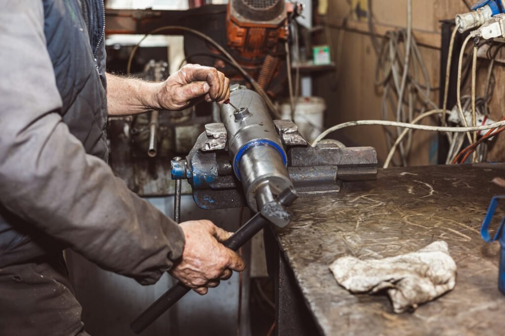 Mechanic repairing spare parts from a tractor. Workshop.